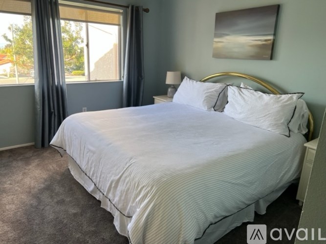 A bedroom with a large bed and a painting on the wall.