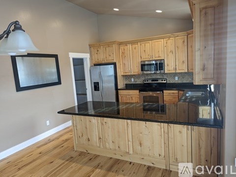 A kitchen with wooden cabinets and black countertops.