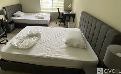 A bedroom with two beds and a desk.