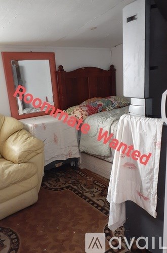 A bedroom with a bed, a chair, and a mirror.