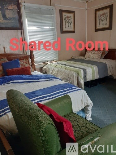 A room with two beds and a green chair is labeled as a shared room.