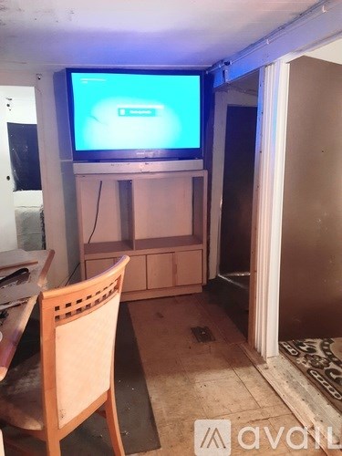 A room with a television on a cabinet and a chair in front of it.