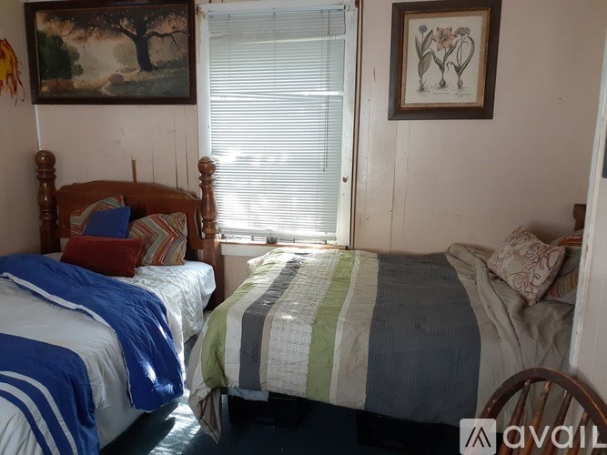 Two beds with striped bedspreads are in a room with a painting on the wall.