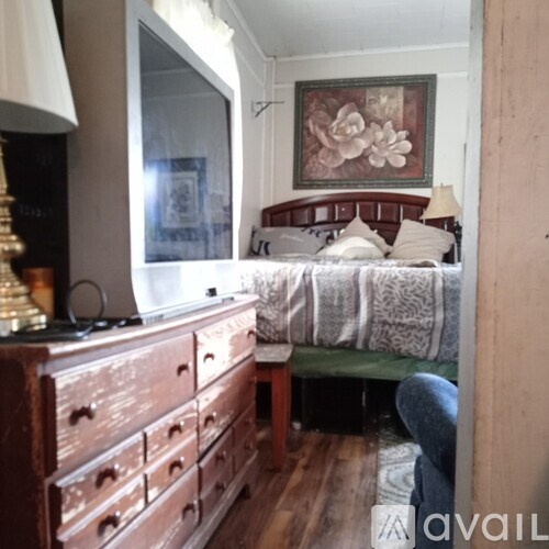 A bedroom with a bed, a dresser, and a painting on the wall.