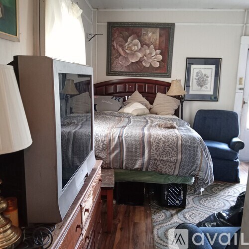 A bedroom with a bed, a chair, and a television.