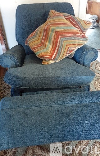 A blue chair with a striped pillow on it.