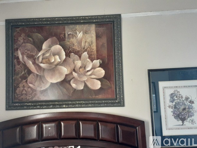A framed artwork of flowers hangs on a wall above a brown headboard.