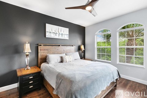 A bedroom with a bed, nightstand, and a ceiling fan.