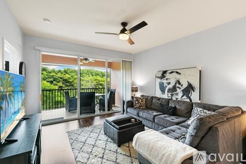 A living room with a grey couch and a painting of a horse on the wall.
