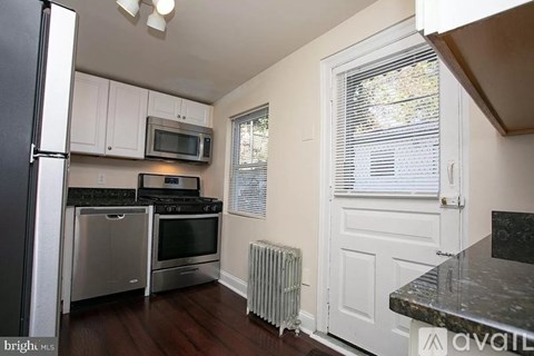 A kitchen with a black counter top and white cabinets.