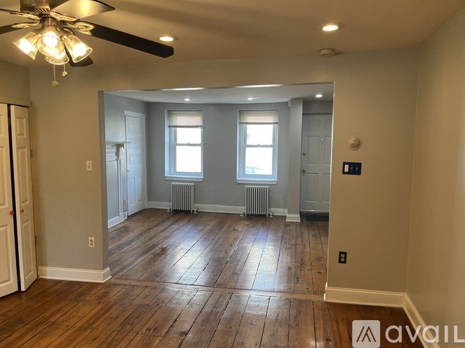 A spacious room with wooden floors and a ceiling fan.