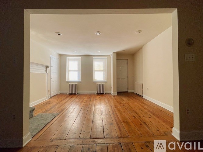 A room with wooden floors and two windows.