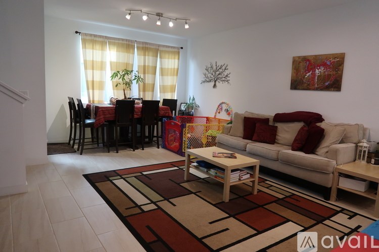 A living room with a sofa, a dining table with chairs, and a rug on the floor.