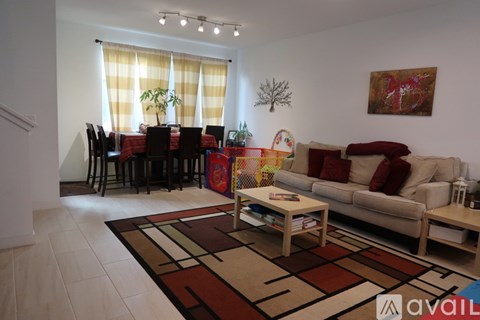 A living room with a sofa, a dining table with chairs, and a rug on the floor.