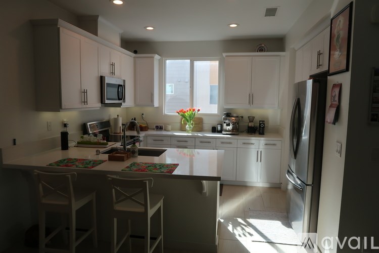 A kitchen with white cabinets and a white refrigerator.