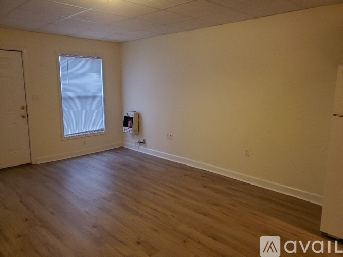 A room with wooden flooring and a window with blinds.