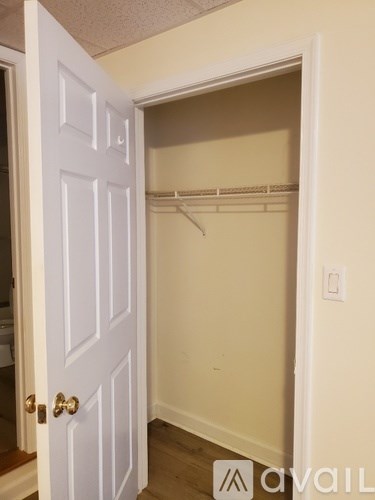 A white door with a gold handle is open to a small closet.