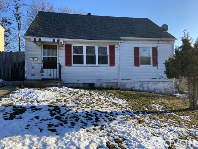 A small white house with red trim and a black roof.