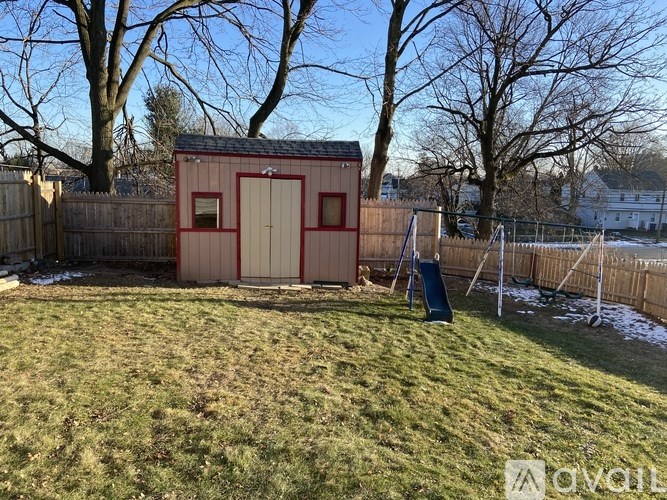A small red shed sits in a backyard with a green slide.
