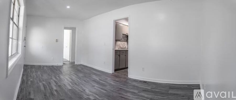 A spacious room with wood flooring and white walls.