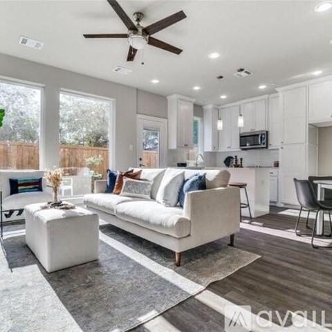 A modern living room with a white sofa and a kitchen area in the background.