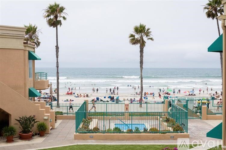 A beach scene with people on the sand and palm trees.