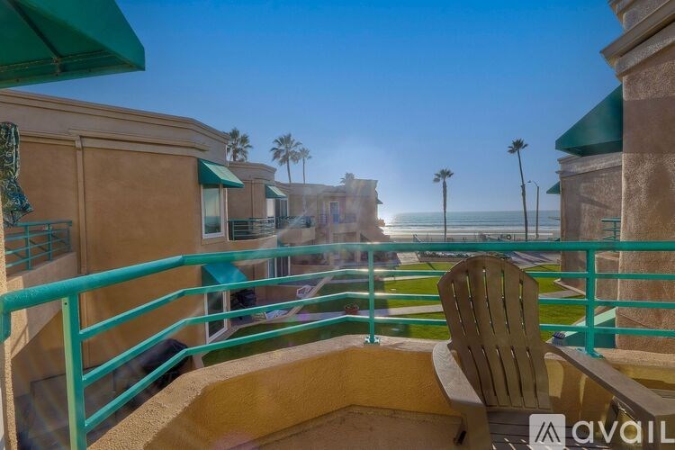 A balcony with a chair and a railing overlooking the ocean.