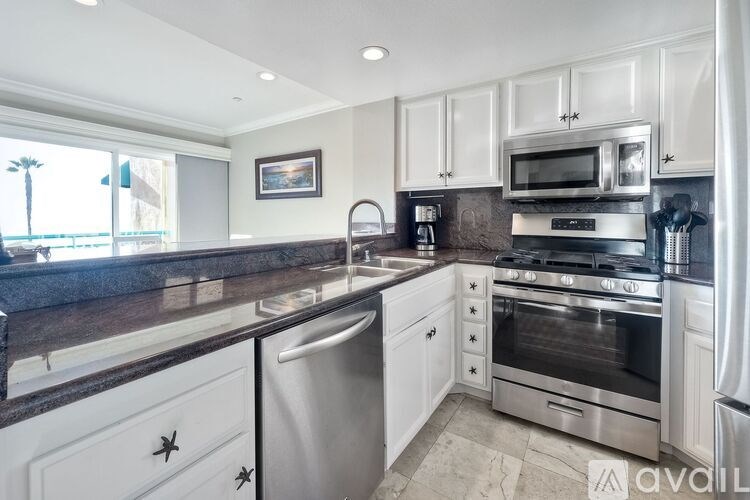 A kitchen with white cabinets and a black countertop.