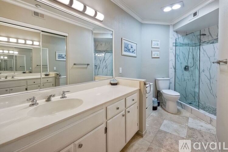 A bathroom with a marble shower and a toilet in the corner.