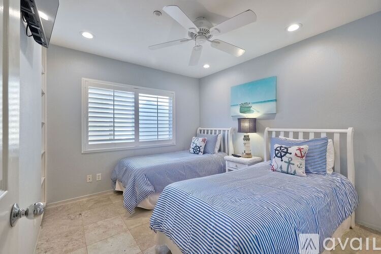 A bedroom with two beds and a ceiling fan.