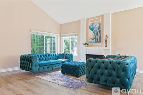 A living room with a green tufted sofa and a fireplace.