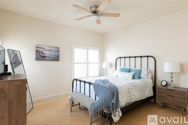 A bedroom with a bed, nightstand, and a ceiling fan.