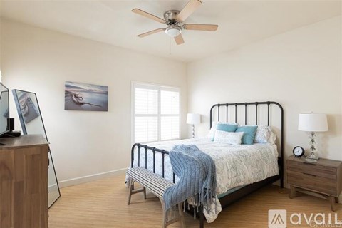 A bedroom with a bed, nightstand, and a ceiling fan.