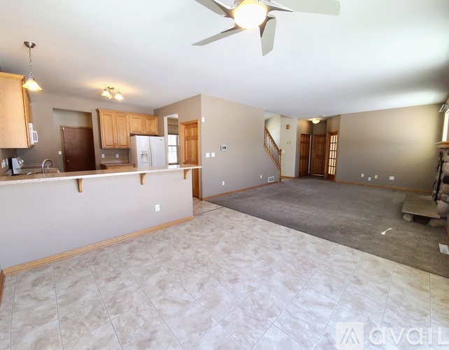 A spacious living room with a kitchen area in the background.