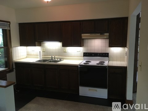 A kitchen with dark brown cabinets and a white stove top oven.