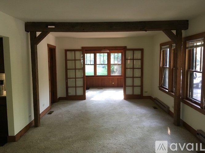 A spacious room with a carpeted floor and large windows.