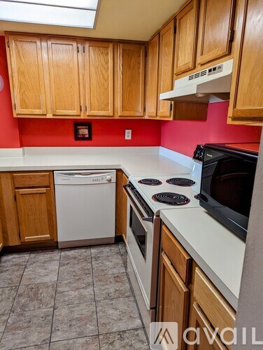 A kitchen with wooden cabinets and a red wall.