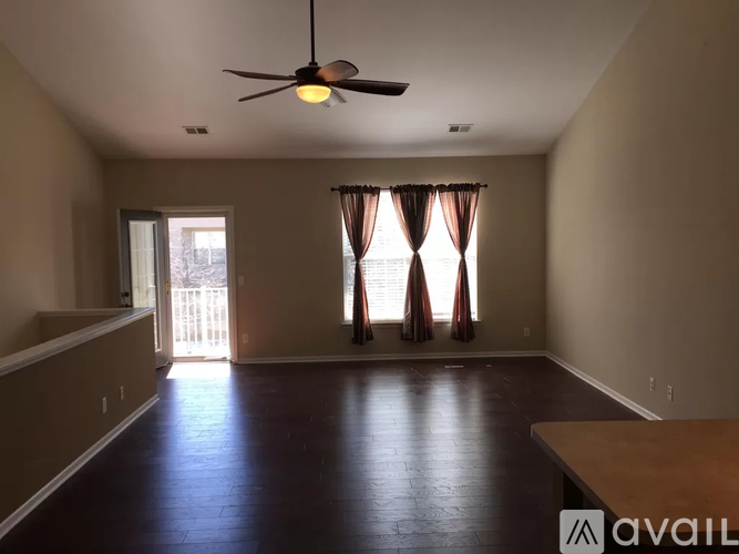 A room with a ceiling fan and a window with curtains.
