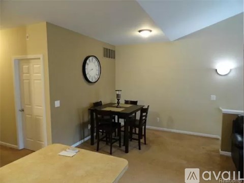 A dining room with a table and chairs and a clock on the wall.
