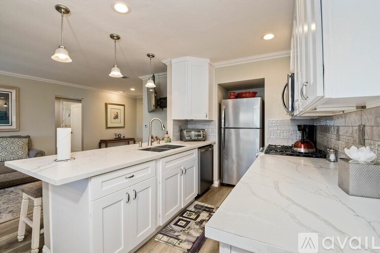A kitchen with white cabinets and a marble countertop.
