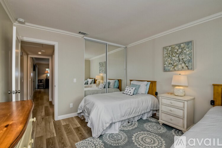 A bedroom with a large bed and a mirrored wall.
