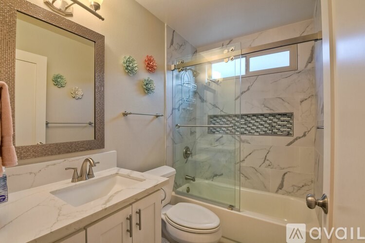 A bathroom with a marble countertop and a glass shower stall.