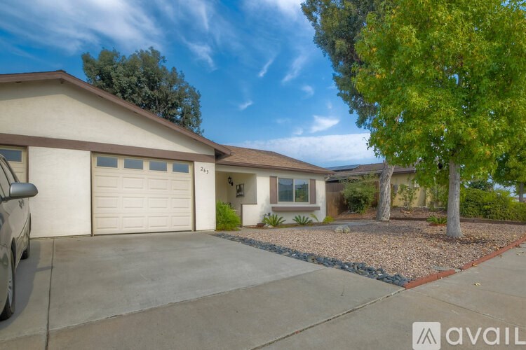 A house with a garage and a tree in front.