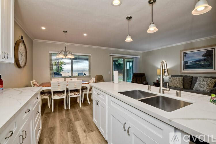 A kitchen with white cabinets and a wooden floor.
