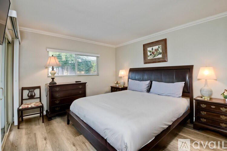 A bedroom with a large bed, a chair, and a window.