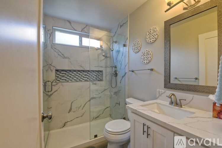 A bathroom with marble tiles and a glass shower stall.