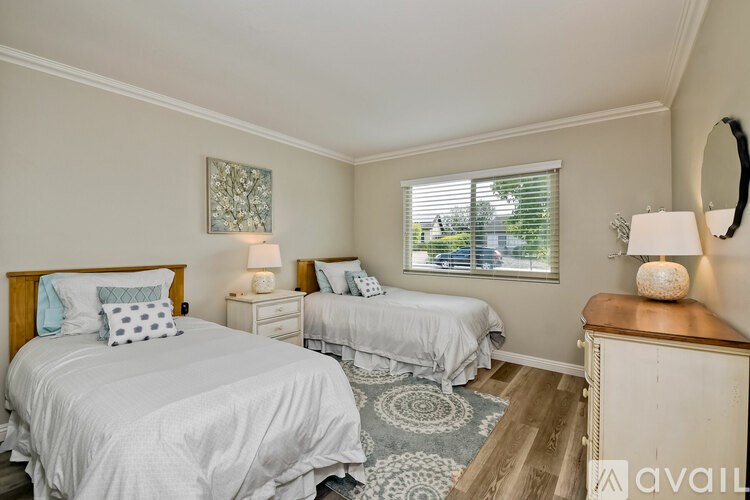 A bedroom with two beds, a dresser, and a mirror.