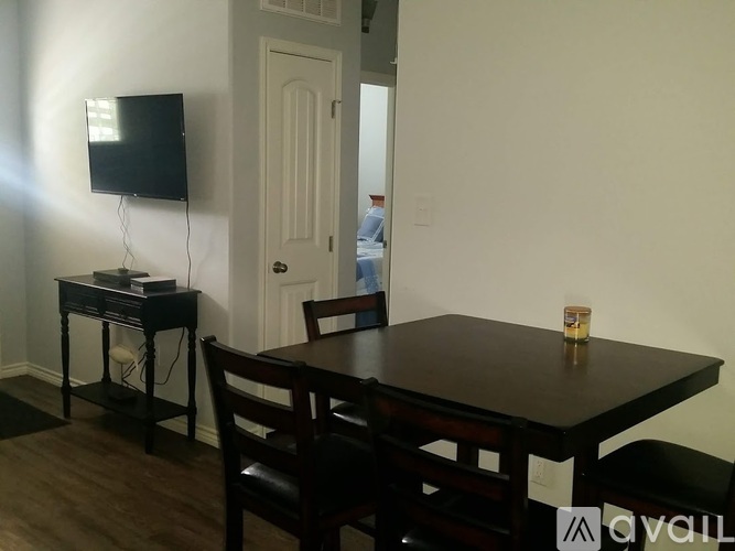 A black table with a television on a stand and a chair in front of it.