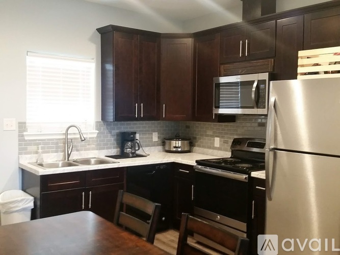 A kitchen with a refrigerator, sink, and stove.