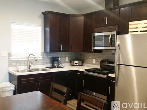 A kitchen with a refrigerator, sink, and stove.